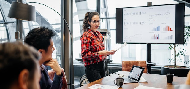 A person presenting data analytics findings to others in a conference room.