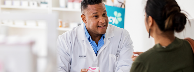 A Butler University pharmacist speaks to a patient across the pharmacy counter.