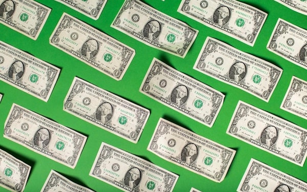 Rows of dollar bills against a green background.