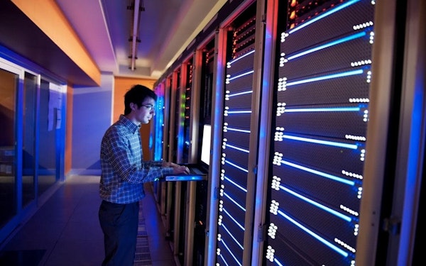 A young network engineer at work in a server room.