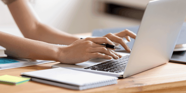 A person's hands typing on a laptop