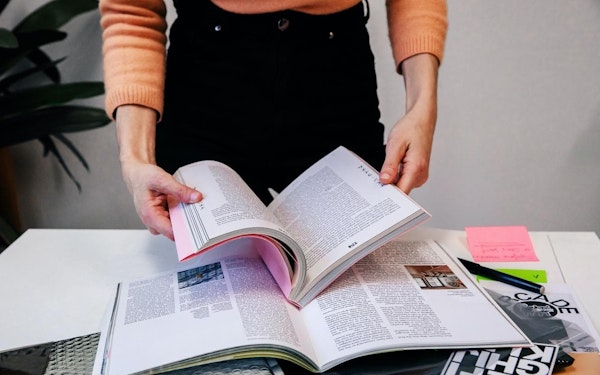 A person opening a book at their work desk.