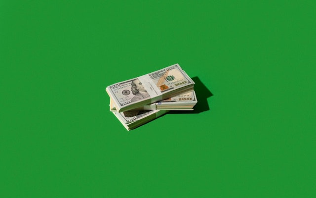 Stacks of hundred-dollar bills against a green background.