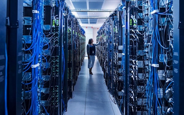 A network engineer standing in the aisle of a server room.