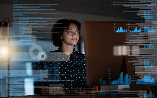 A network engineer reviews data and graphs at their desktop computer.