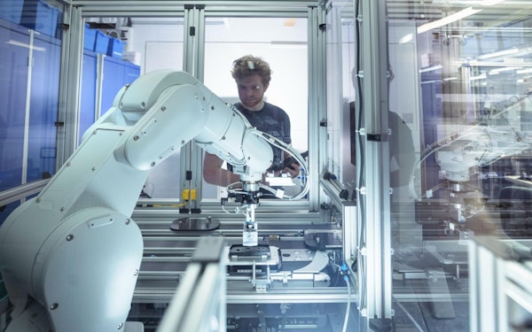 A man looks at an artificial intelligence machine through a clear glass divider.