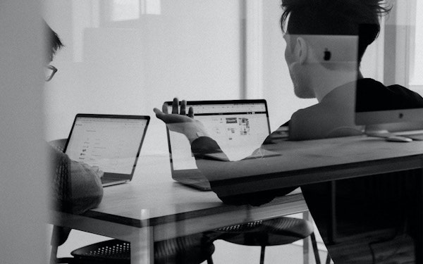 Two coworkers at their laptops in a conference room.