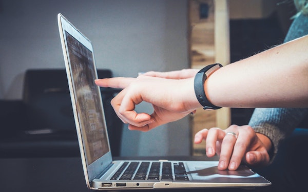 A student points at information on their laptop screen.