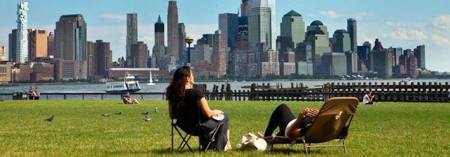 Students in lawn chairs enjoy riverline views of the New York City skyline.